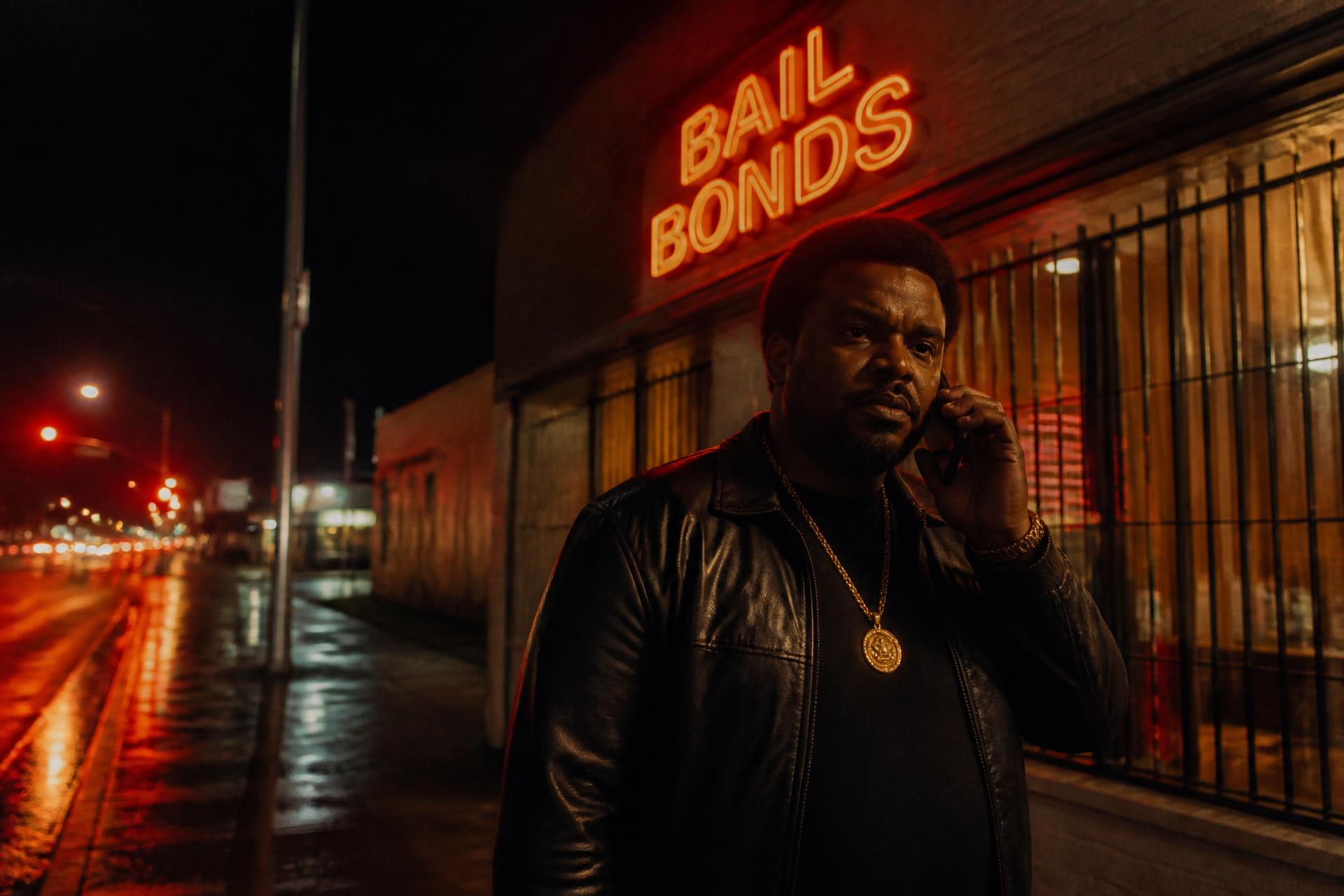 Bail bonds storefront glowing at night, agent on the phone under the neon sign